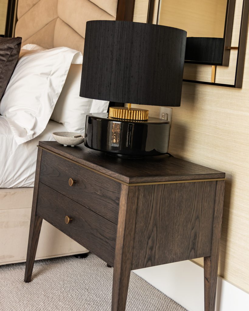 Black Lamp on a beautiful wooden 2-drawer bedside table in a luxury bedroom design. 